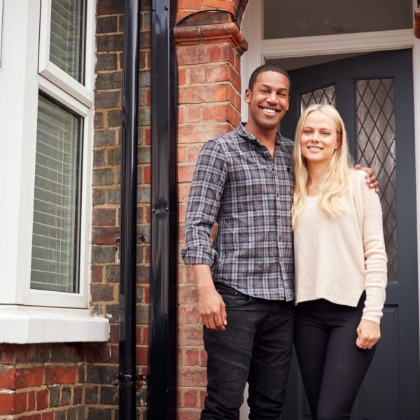 Portrait Of Proud Young Couple Standing Outside First Home Together