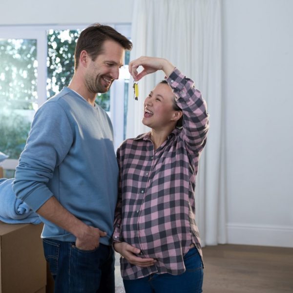 Pregnant couple holding key to their new home, exploring mortgage solutions and family planning in Ontario - Mortgage Scout